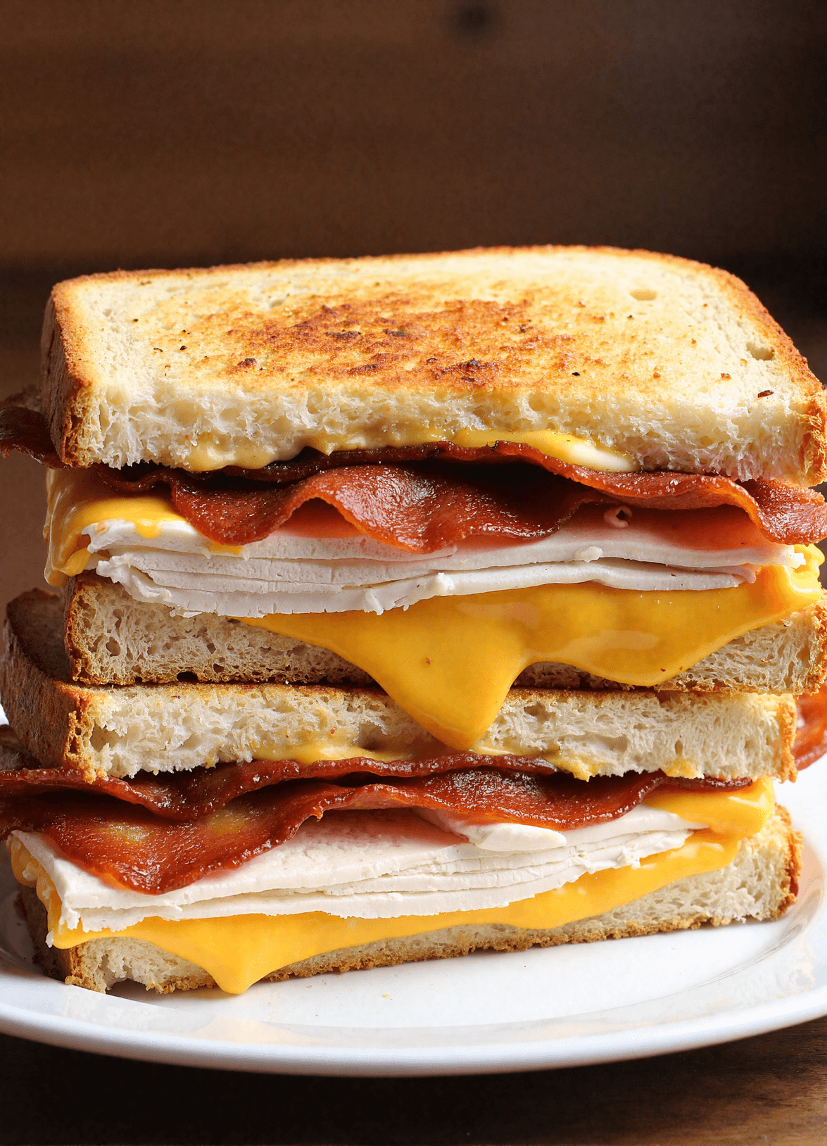 Stacked cheddar and bacon turkey melt on sourdough bread with gooey cheddar, crispy bacon, and sliced turkey breast
