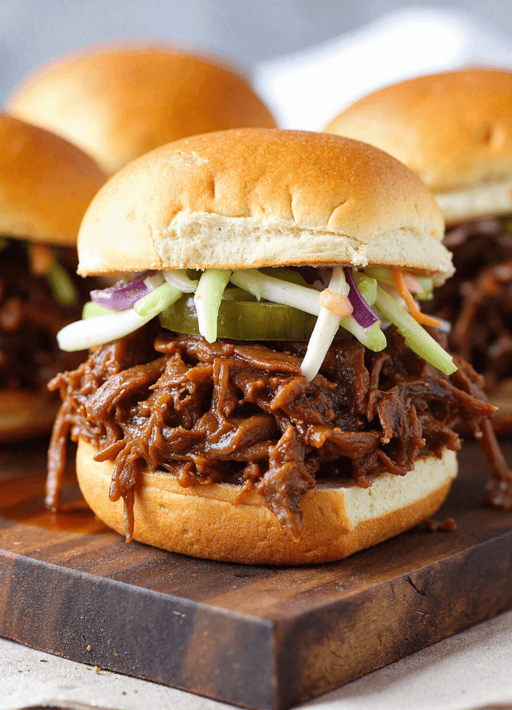 Slow cooker chipotle brisket sliders with barbecue sauce, pickles, and creamy coleslaw served on soft slider buns.