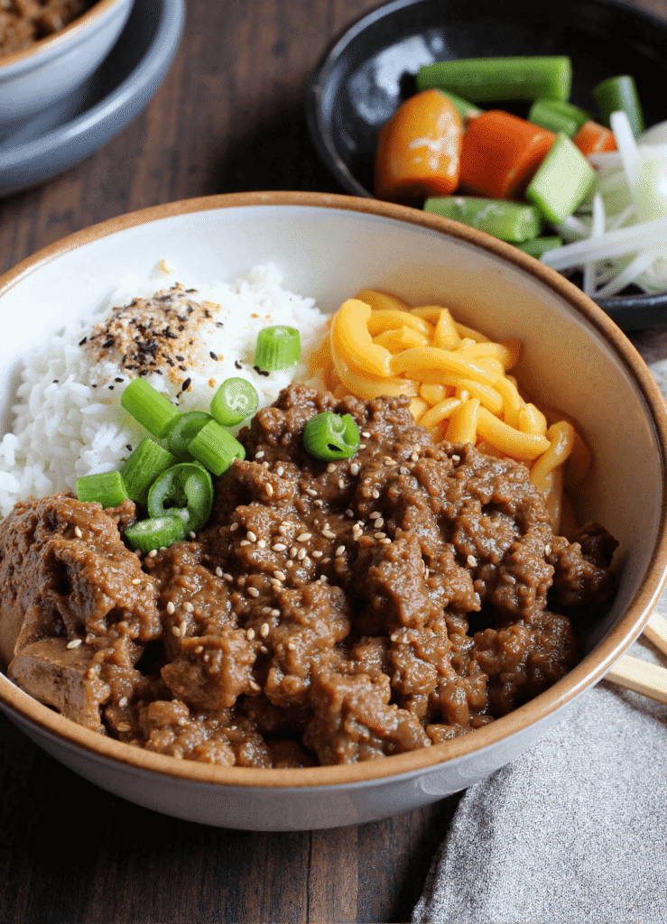 Korean ground beef bowl with steamed rice, seasoned ground beef, cheese, and green onions in a ceramic bowl