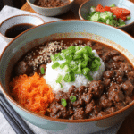 Korean ground beef bowl with jasmine rice, gochujang beef, shredded carrots, and green onions served in a rustic ceramic bowl