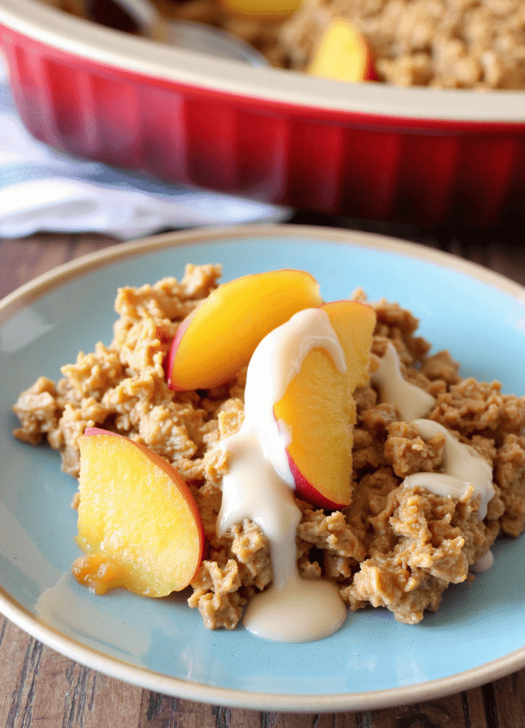 A plated serving of peaches ‘n cream baked oatmeal topped with fresh peach slices and a drizzle of cream
