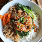 Sticky ginger tofu over white rice and brown rice, served with bok choy, sesame seeds, and julienned carrots.
