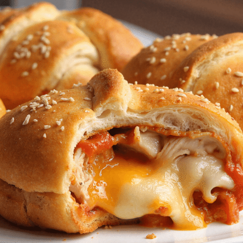 Close-up of a chicken parmesan pillow revealing melted mozzarella, cheddar, and marinara inside flaky crescent dough.