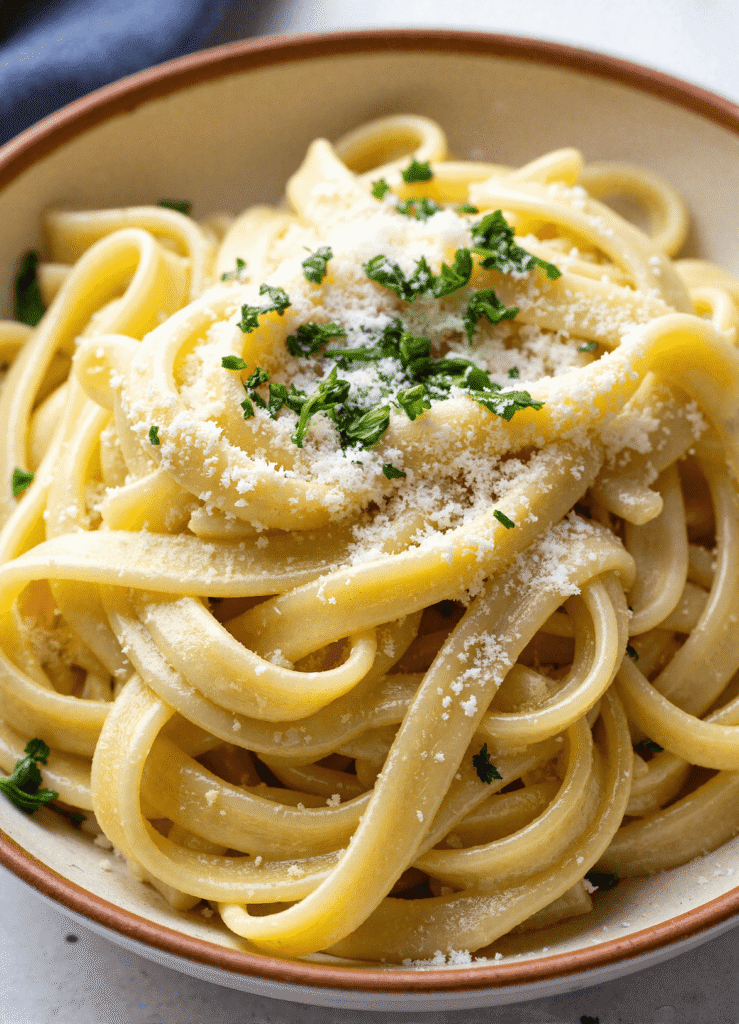 Bowl of linguine tossed in garlic butter sauce with parmesan and herbs