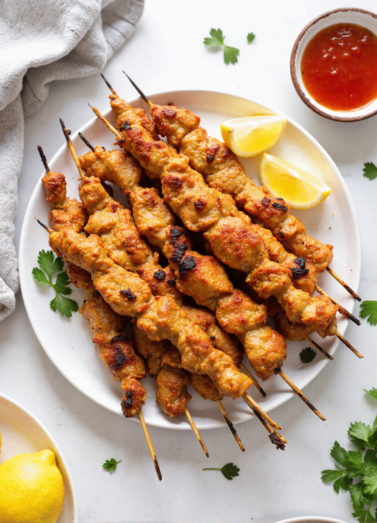 Platter of grilled-style air fryer chicken skewers served with lemon wedges and dipping sauce