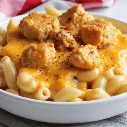 Close-up of baked mac and cheese with creamy chicken pieces and pepper seasoning in a bowl.
