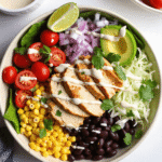 Colorful Southwest Chicken Salad Bowl filled with grilled chicken, black beans, corn, tomatoes, avocado, and Greek yogurt dressing on lettuce.