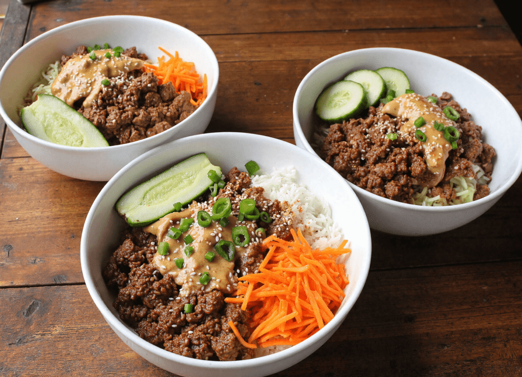 Three viral ground beef bowls with rice, shredded carrots, cucumbers, scallions, and creamy peanut drizzle—perfect for family dinners or batch meal prep.