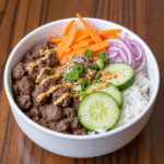 Ground beef dinner bowl with white rice, cucumbers, shredded carrots, red onions, and spicy drizzle – a high-protein, meal prep–friendly comfort food.