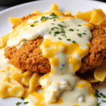 Crispy parmesan chicken breast topped with creamy white cheese sauce and cheddar drizzle, served over buttered pasta.
