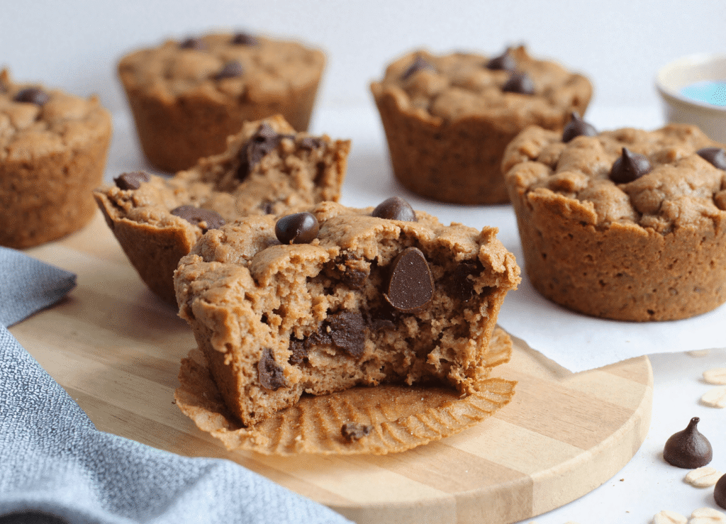 Chocolate chip-studded Greek yogurt oatmeal cups with a fluffy interior, one broken open to show soft texture and melty chocolate.