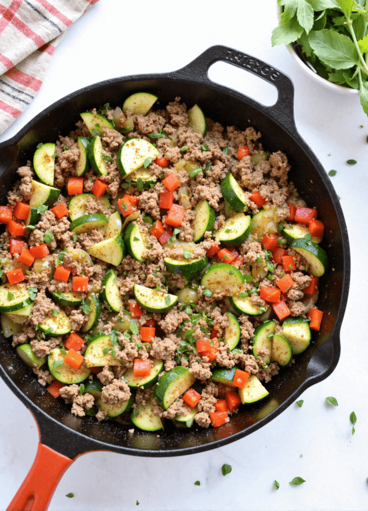 Overhead shot of ground turkey and zucchini skillet with red bell peppers in a cast iron pan, a quick low-carb one-pan dinner