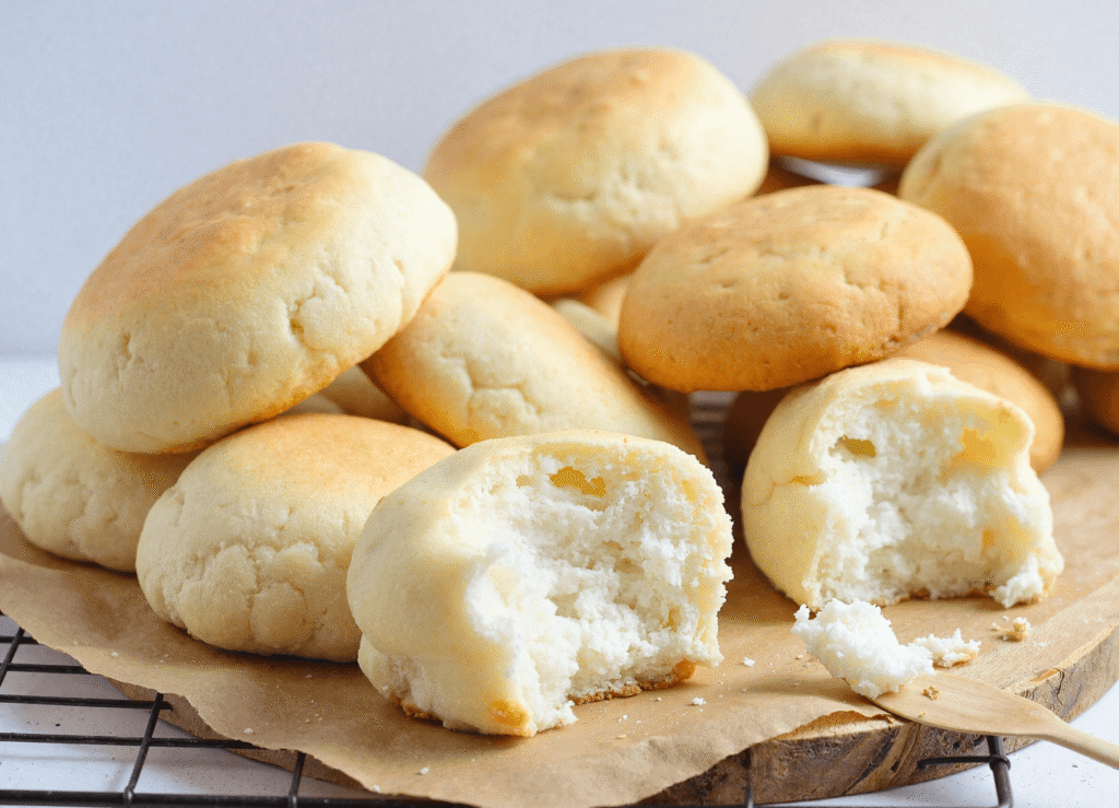 Golden-brown cottage cheese cloud bread pieces stacked on a cooling rack, with soft, fluffy insides.