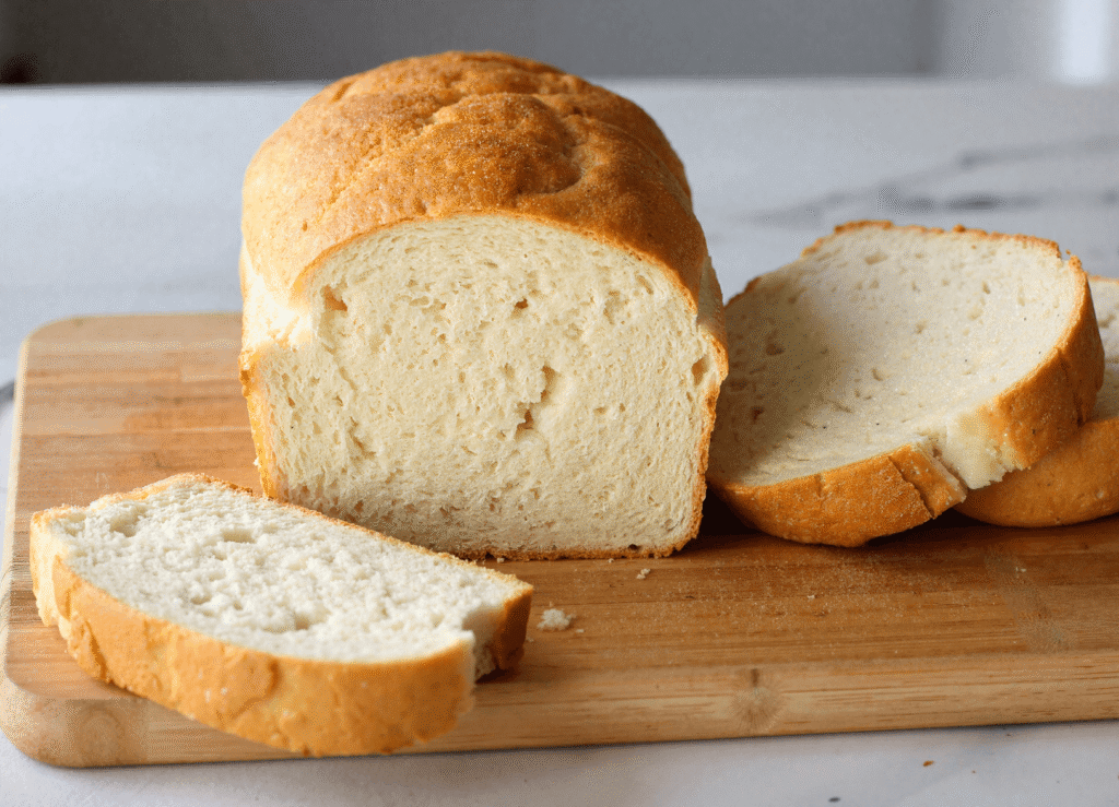 Sliced loaf of fluffy, golden-brown yogurt bread on a wooden cutting board, showcasing its airy, keto-friendly crumb.