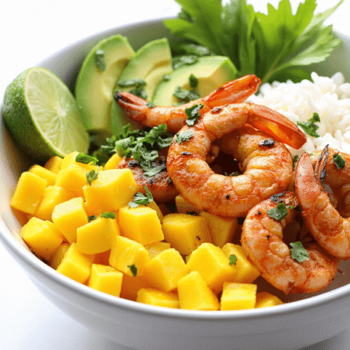 Grilled shrimp rice bowl with mango, avocado, fresh herbs, and lime in a white ceramic bowl.